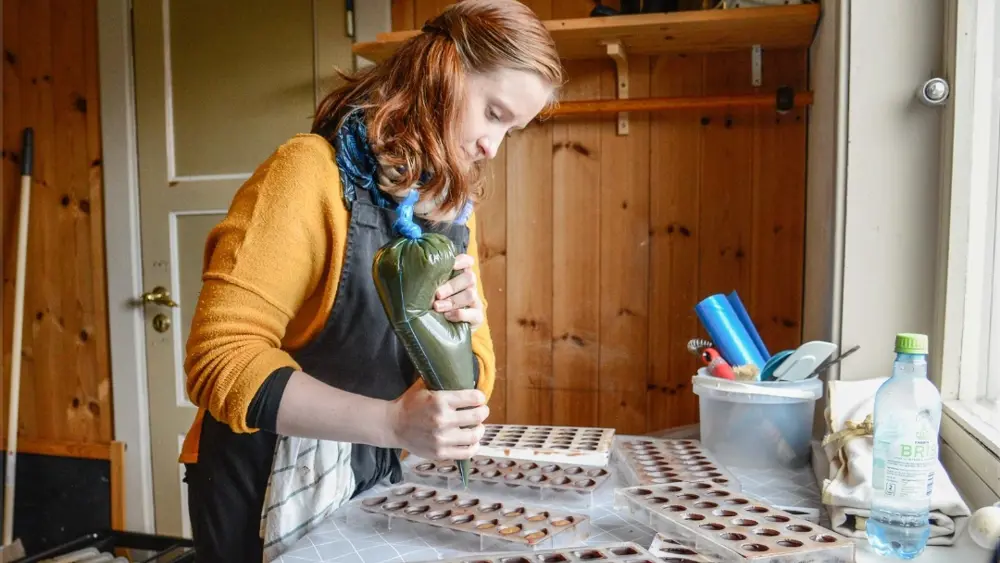 Tone Log fills chocolate into molds. 