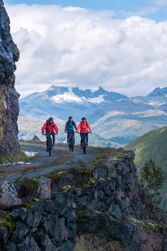 Syklister på Tusenmeteren med fjellene i Hurrungane som bakteppe