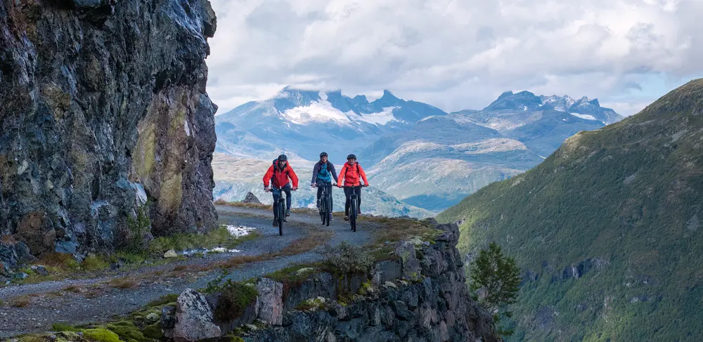 Syklister på Tusenmeteren med fjellene i Hurrungane som bakteppe
