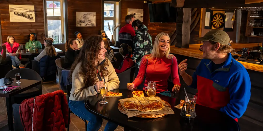 Venner som nyter pizza og noe godt i godt i glasset i Fjellpuben på Filefjellstuene