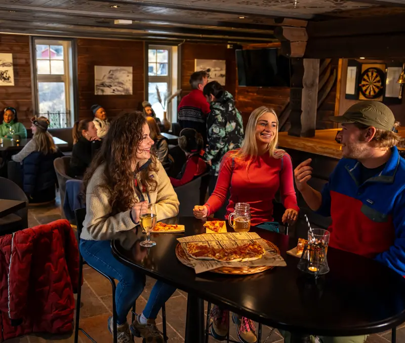 Venner som nyter pizza og noe godt i godt i glasset i Fjellpuben på Filefjellstuene