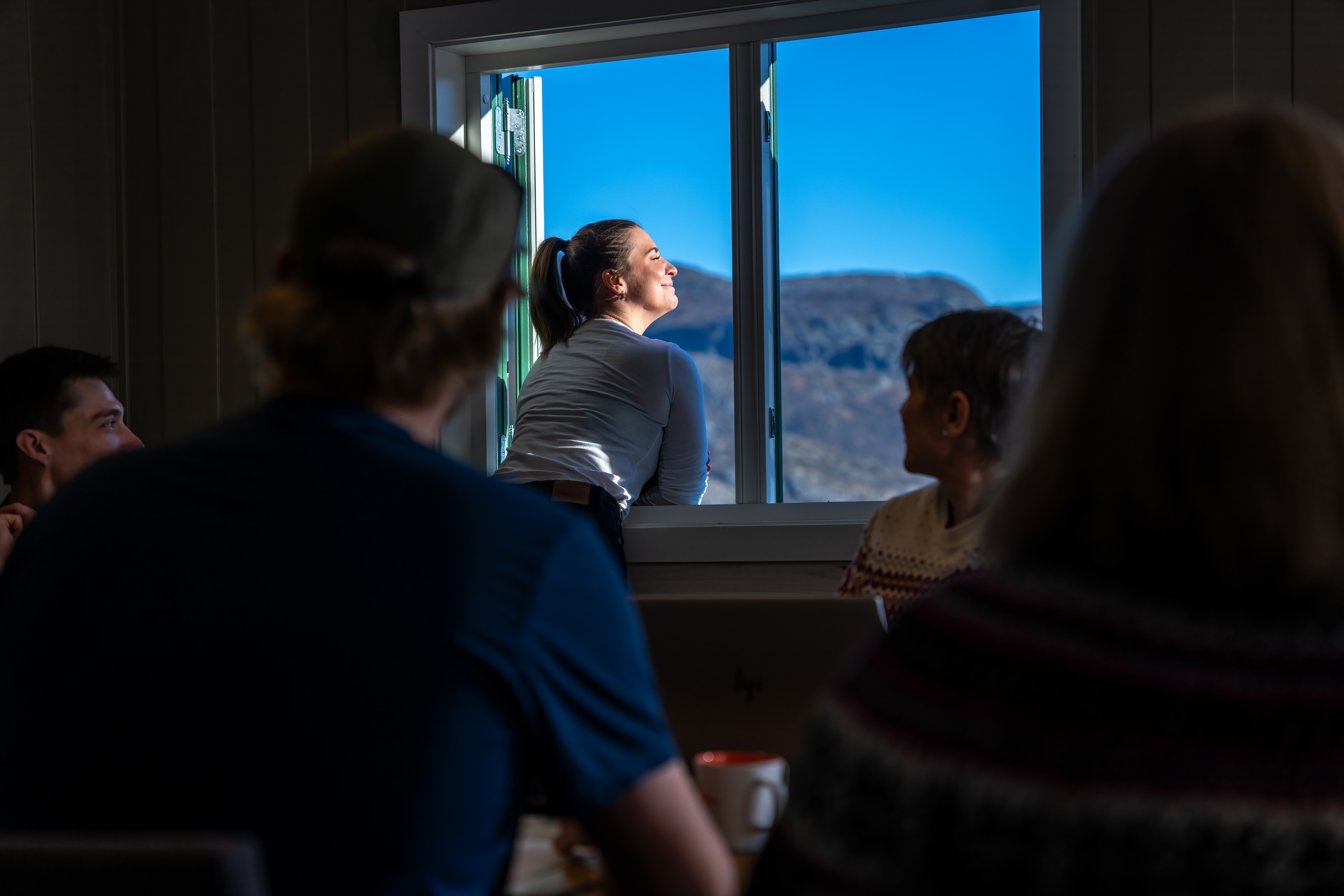 Break in meeting – participant enjoys mountain air from the window at Filefjellstuene, while others sit together around the table