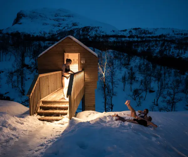 Venner bader i snøen utenfor badstuen på Filefjellstuene en vinterkveld