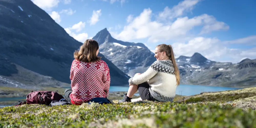 Venner som tar en pause på tur i Koldedalen, men Falketind i bakgrunnen