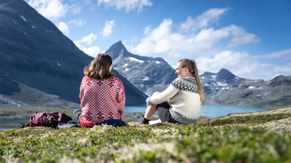 Venner som tar en pause på tur i Koldedalen, men Falketind i bakgrunnen
