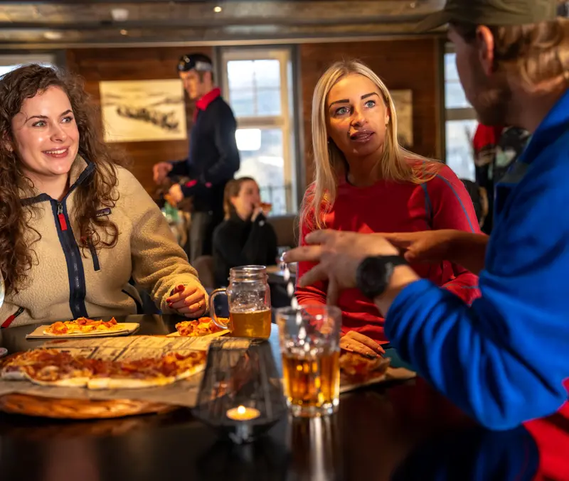 Venner som nyter pizza og noe godt i godt i glasset i Fjellpuben på Filefjellstuene
