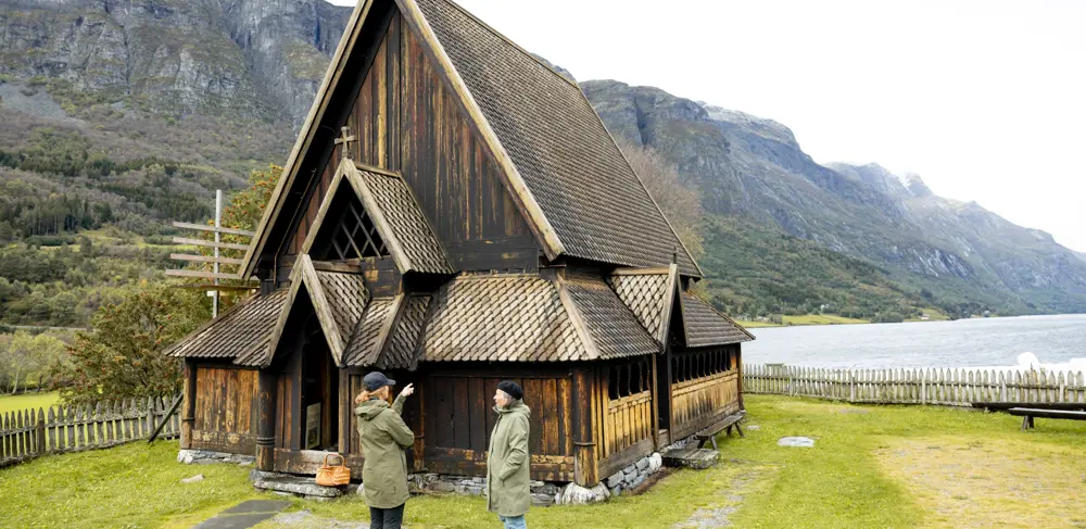 Gjest og guide utenfor Øye Stavkyrkje i Vang