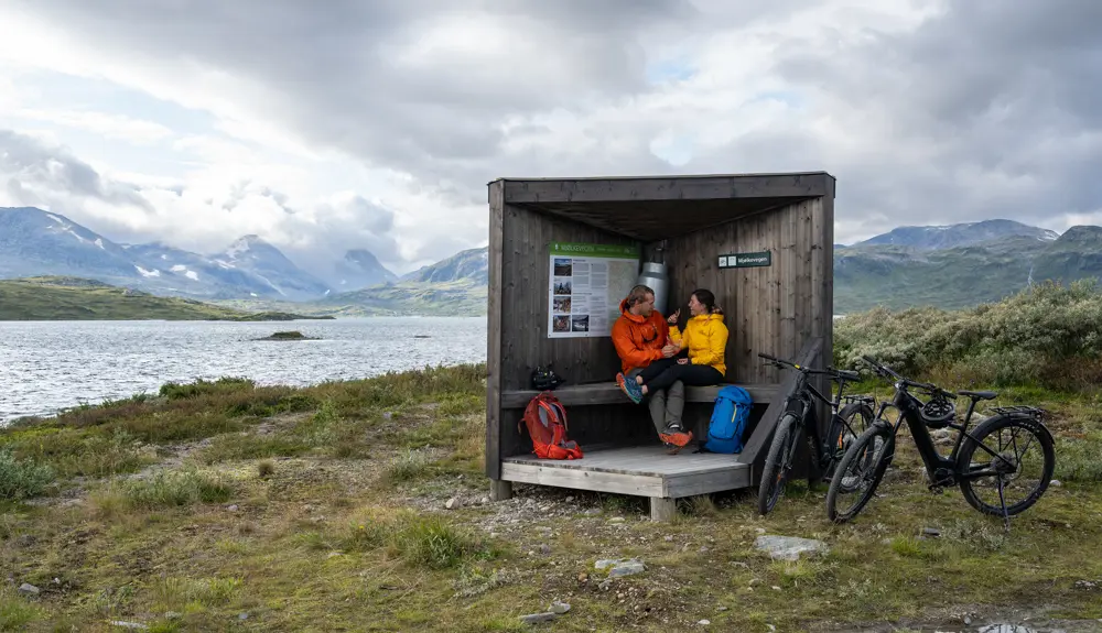 Young couple on a bike ride on the Mjølkevegen along Tyin taking a lunch break at an information point
