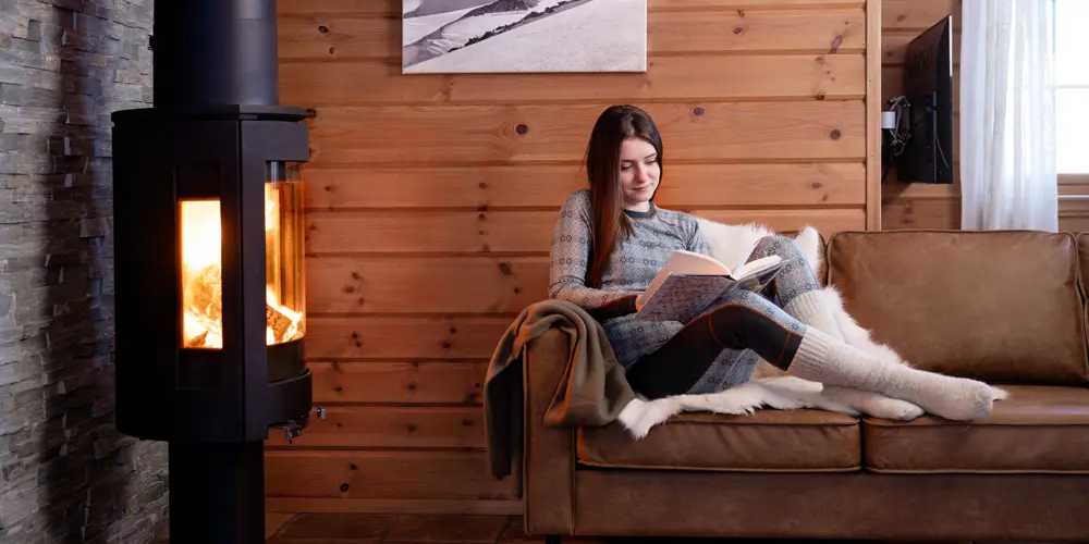 Woman reading a good book by the fireplace in one of the apartments at Filefjellstuene